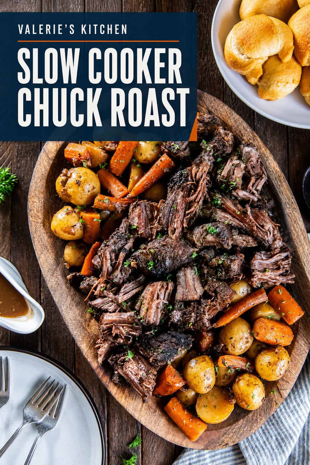 Tender slow cooker chuck roast with carrots and baby potatoes on a wooden serving platter, garnished with fresh parsley and served with gravy with bold title text overlay.