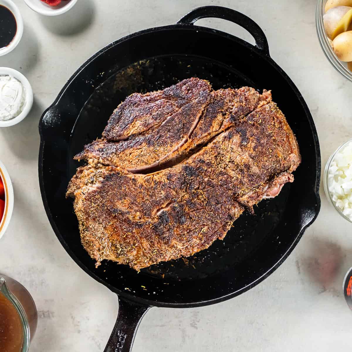Seared beef chuck roast in a cast iron skillet.