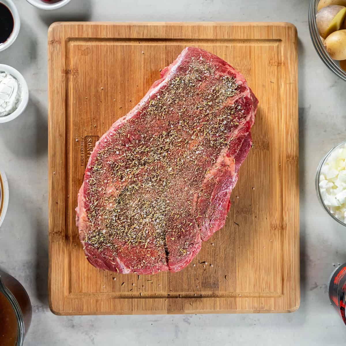 Seasoned beef chuck roast on a cutting board.