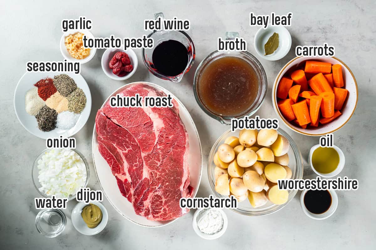 Ingredients for Slow Cooker Chuck Roast, including beef, potatoes, carrots, onion, garlic, red wine, beef broth, herbs, and seasonings.
