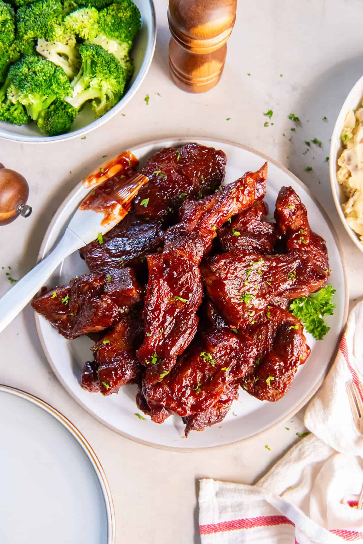 Slow Cooker Country Style Ribs coated in sticky, caramelized BBQ sauce with a sauce-covered pastry brush alongside.