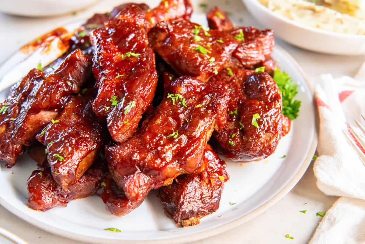 Sticky, caramelized Slow Cooker Country Style Ribs garnished with parsley on a serving platter.