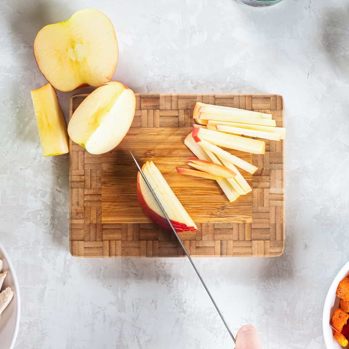 Cutting thin apple slices into matchsticks with a sharp knife.