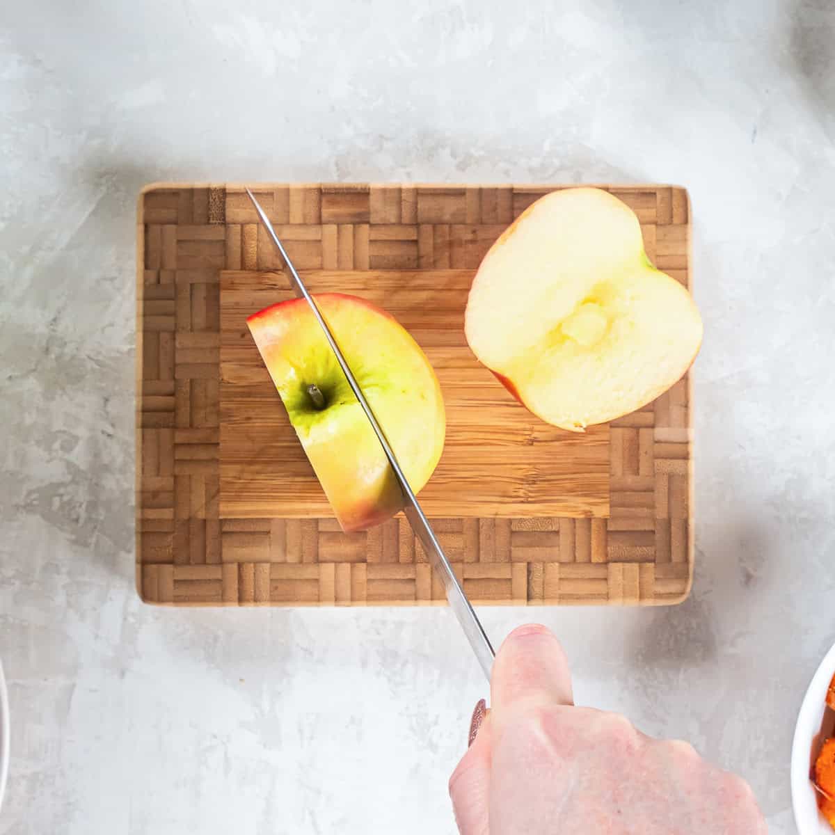 Cutting around the core of an unpeeled apple to prepare it for slicing into matchsticks.