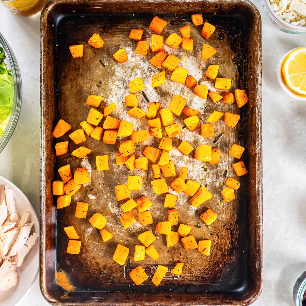 Roasted butternut squash cubes with lightly caramelized edges on a baking sheet.