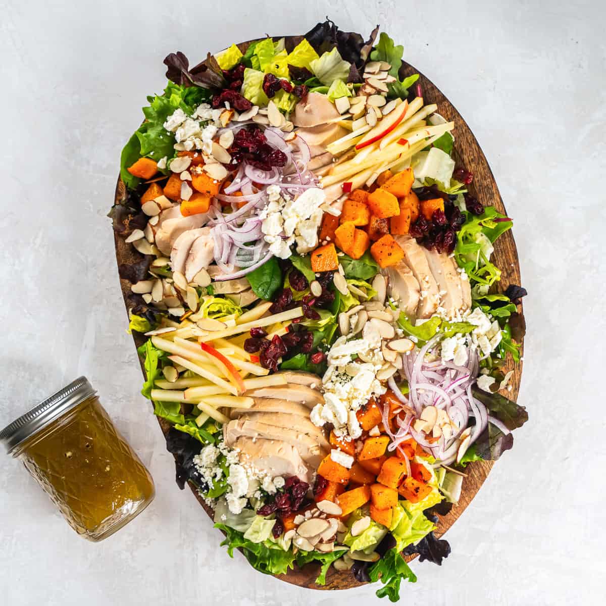 Roasted butternut squash salad with sliced rotisserie chicken, apple matchsticks, dried cranberries, red onion, feta, and sliced almonds over mixed greens.