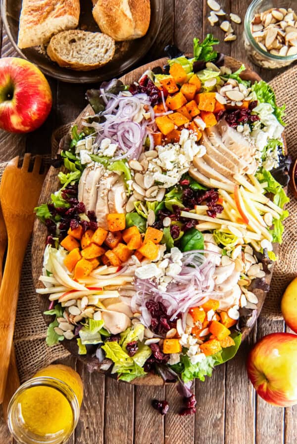 Roasted butternut squash salad with chicken, crisp apples, dried cranberries, sliced almonds, feta cheese, and red onion on a bed of mixed greens, served with maple Dijon vinaigrette.