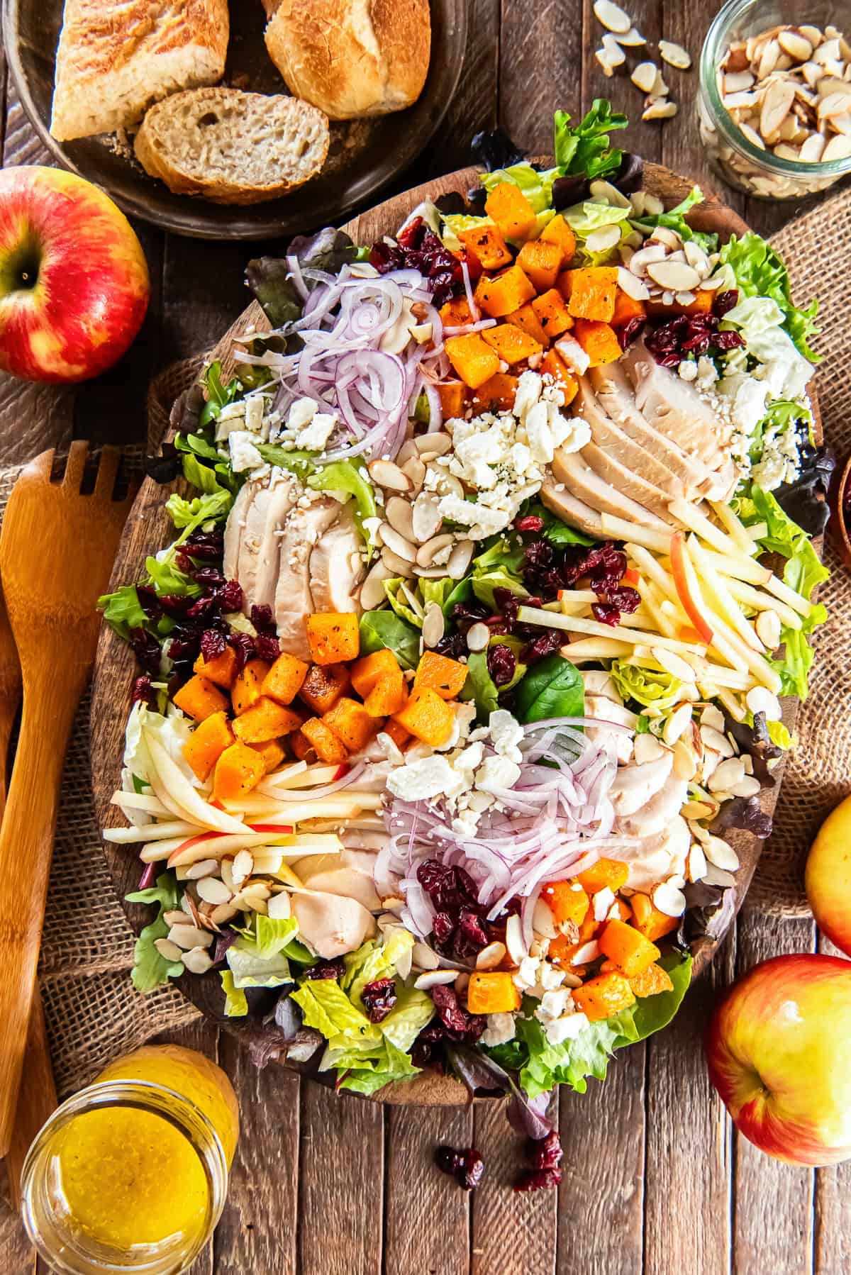Roasted butternut squash salad with chicken, crisp apples, dried cranberries, sliced almonds, feta cheese, and red onion on a bed of mixed greens, served with maple Dijon vinaigrette.