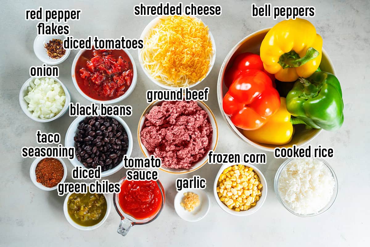 Ingredients for Mexican Stuffed Peppers, including colorful bell peppers, ground beef, rice, black beans, corn, tomatoes, shredded cheese, and seasonings.