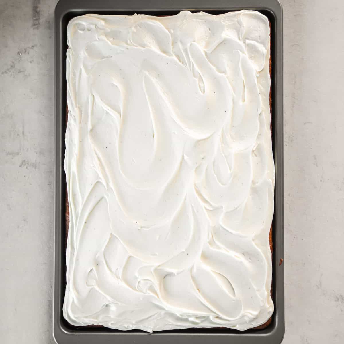 Pumpkin bars in a rimmed baking sheet topped with cream cheese frosting.